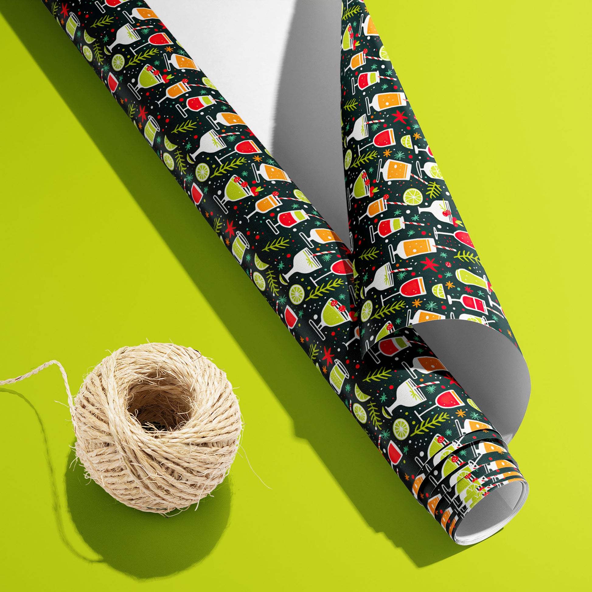 curled roll of Christmas Cocktails wrapping paper revealing its white underside beside a spool of natural twine on a bold lime green background.