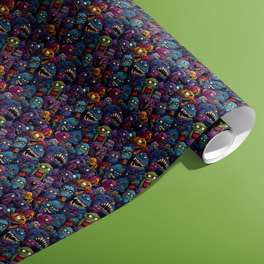 A partially unfurled roll of Odd Monsters gift wrap displays dense, comic monsters with grins and googly eyes on a dark ground against an olive green background.