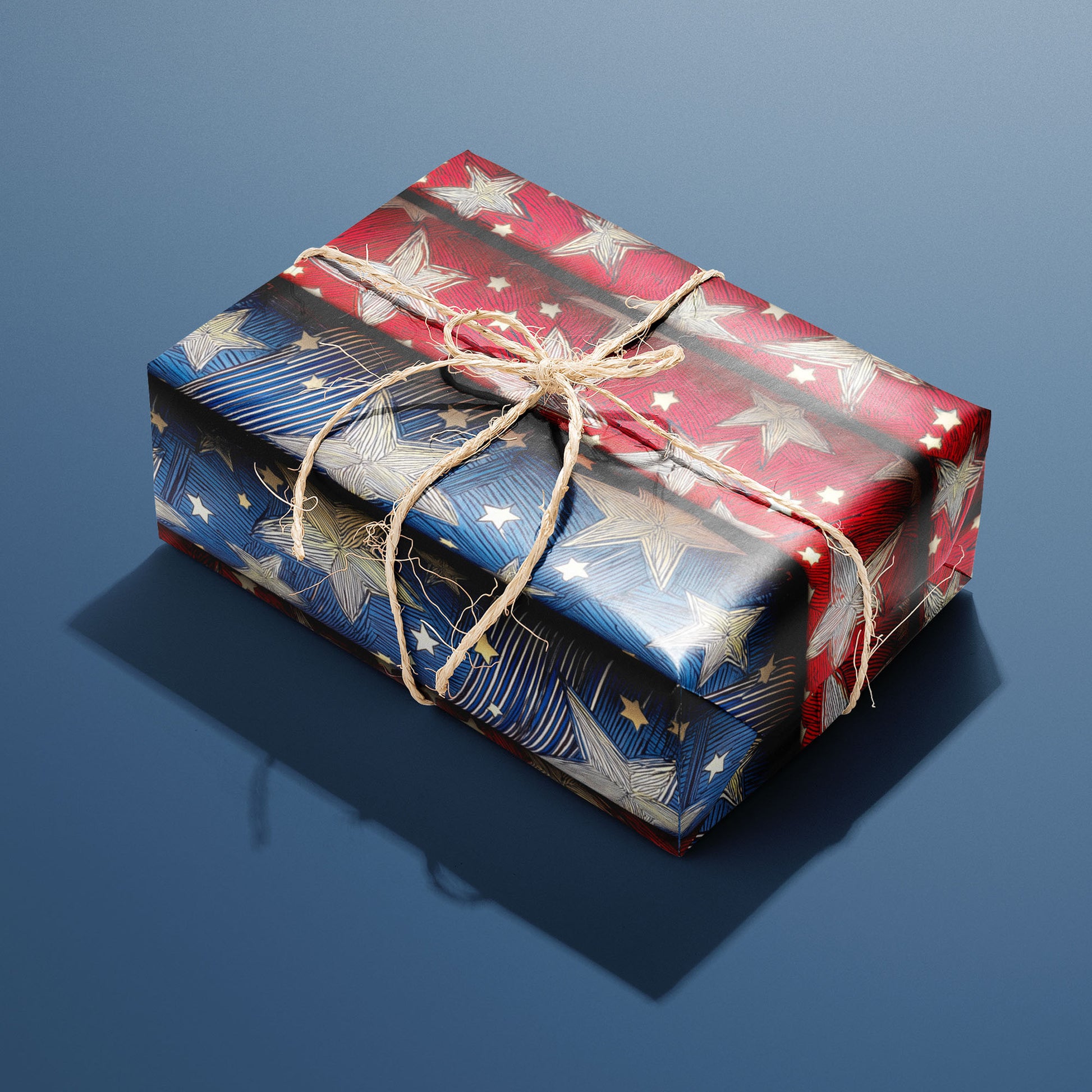 A single rectangular gift wrapped in Starwoven Glory and tied with natural twine highlights embroidered star motifs on a midnight blue ground against a deep navy backdrop.