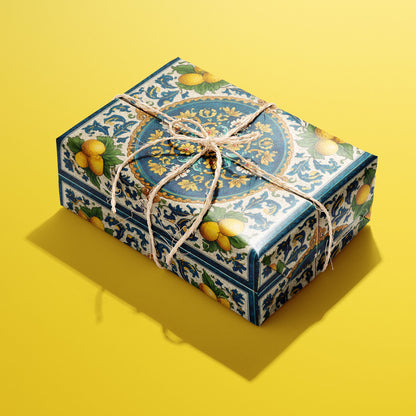 A rectangular gift wrapped in Citron Azulejo paper, the lemon-and-azulejo tile design tied with a natural twine bow, set on a bold yellow background.