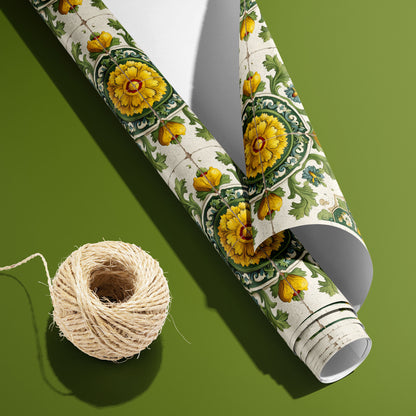 A partially unfurled roll of Golden Girasole wrapping paper with the white underside visible beside a spool of natural twine on an olive green backdrop, patterned with sunflower tiles.