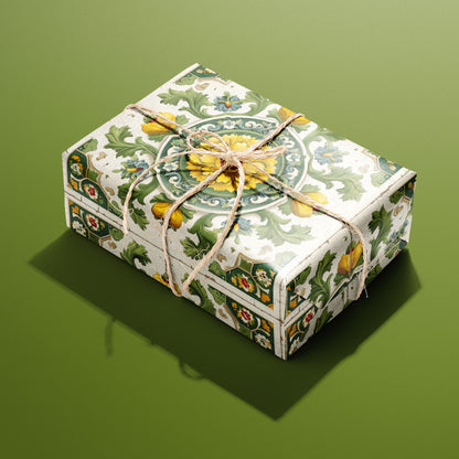 A rectangular gift wrapped in Golden Girasole paper, the sunflower-and-scrollwork tile design tied with a natural twine bow, set on an olive green background.