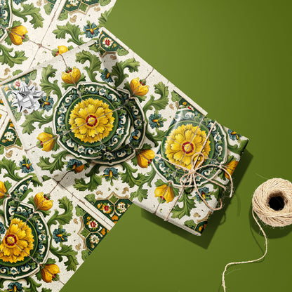 Two gifts wrapped in Golden Girasole paper—one with a silver bow, one tied in twine—rest on two unused sheets beside a twine spool on an olive green surface.