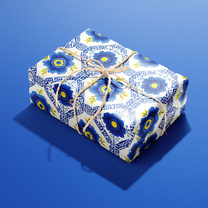 A single box wrapped in Santorini Floriate, its blue floral tile pattern bright on white and tied with natural twine, resting on a saturated blue background.