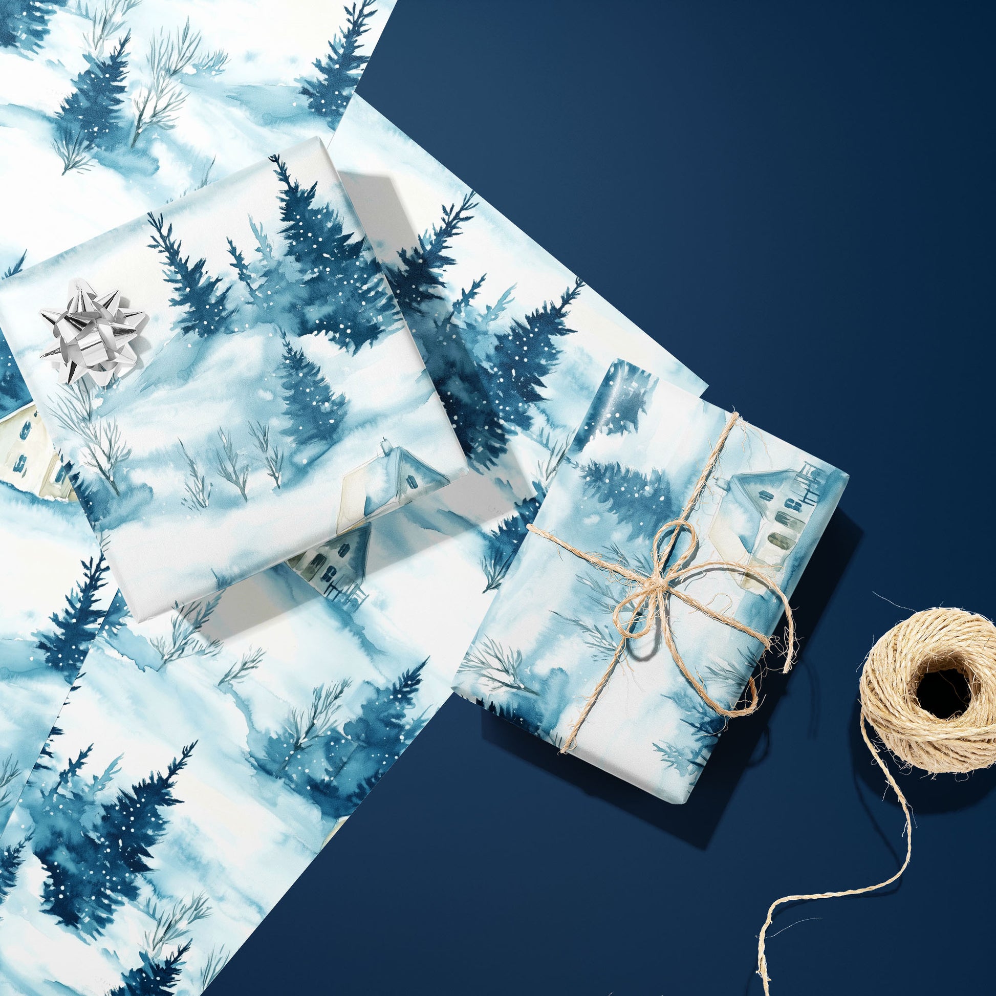Two gifts wrapped in Cozy Cottage winter-village paper, one topped with a silver bow and one tied with twine, resting on extra sheets beside twine on a navy surface.
