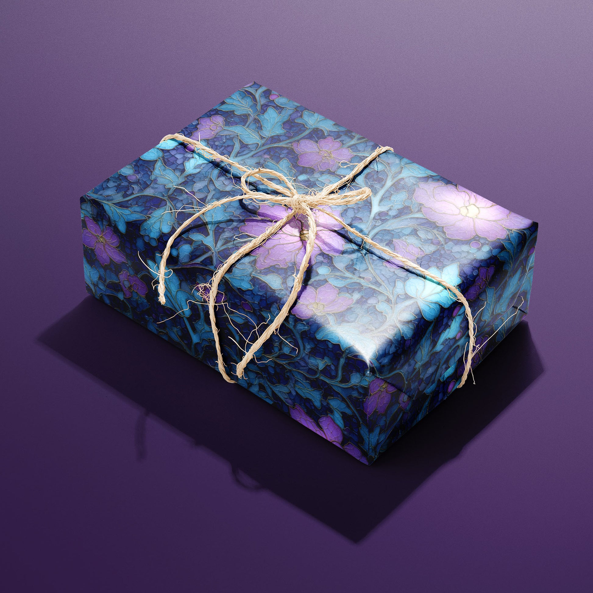 A single gift wrapped in Lunar Hellebore and tied with natural twine, featuring violet hellebore flowers and teal leaves on midnight blue, set on a deep purple surface.