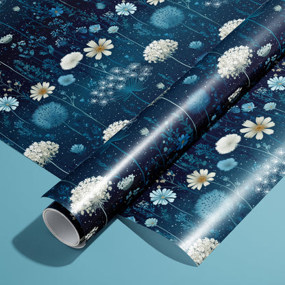 A roll on an unrolled sheet of Midnight Garden wrapping paper with nocturnal florals, butterflies, and starry speckles on deep navy, set on a teal background.